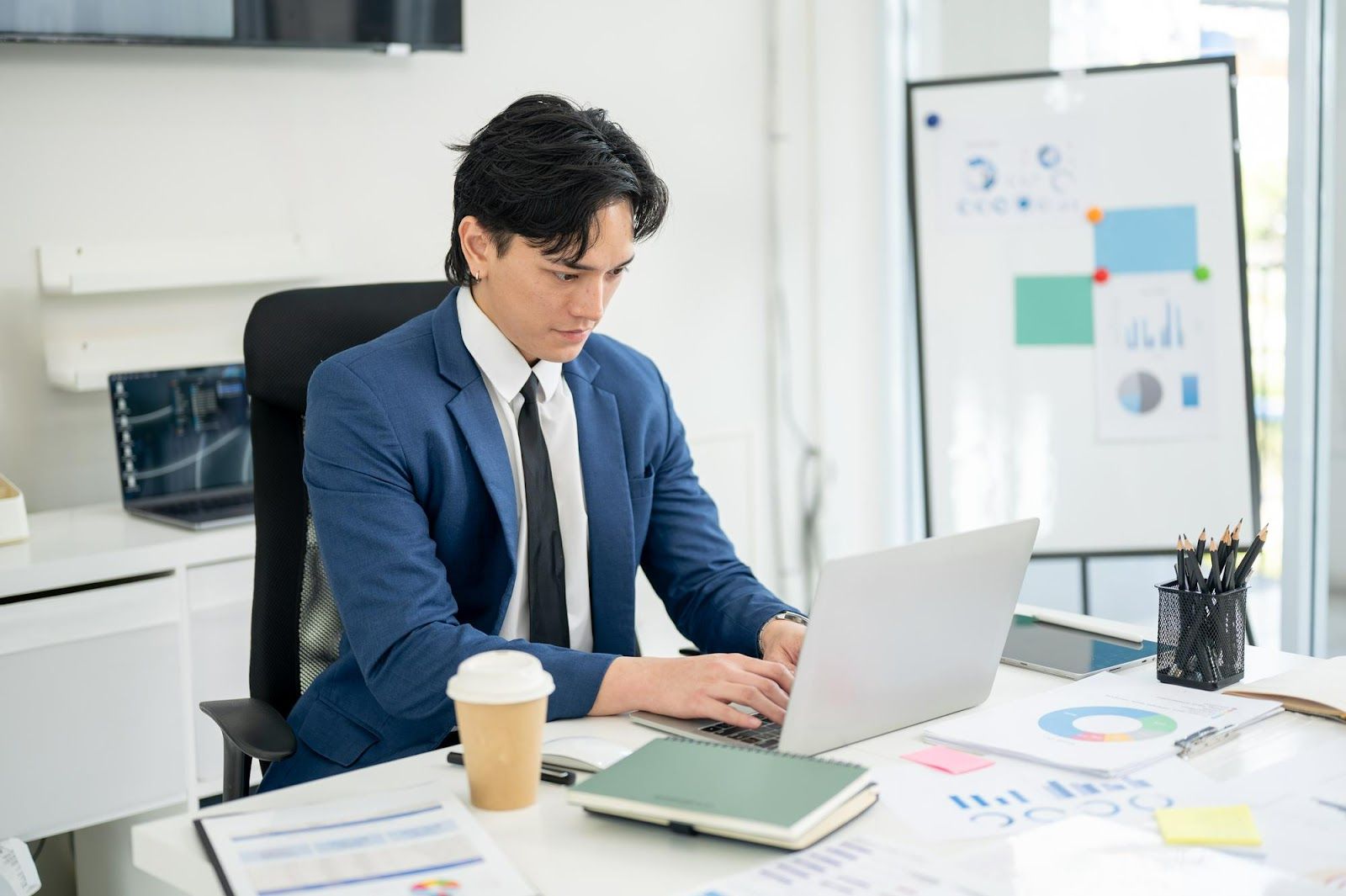 A person in a suit sitting at a desk using a computerAI-generated content may be incorrect.